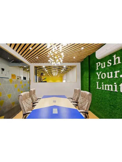 This meeting room uses a faux grass wall with 'Push Your. Limit' lettering to create an energizing and unconventional atmosphere. The wood-slatted ceiling adds warmth and texture, balancing the playful elements with sophisticated design.