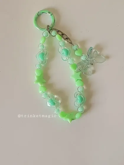 A close-up of the pastel green beaded charm, featuring hearts, stars, and a translucent butterfly. It's a fresh and vibrant accessory, perfect for spring and summer.