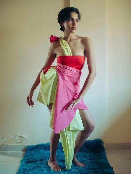 A full-body shot showcasing the improvised dress made from two shirts. The model's dynamic pose highlights the drapery and flow of the unconventional garment.