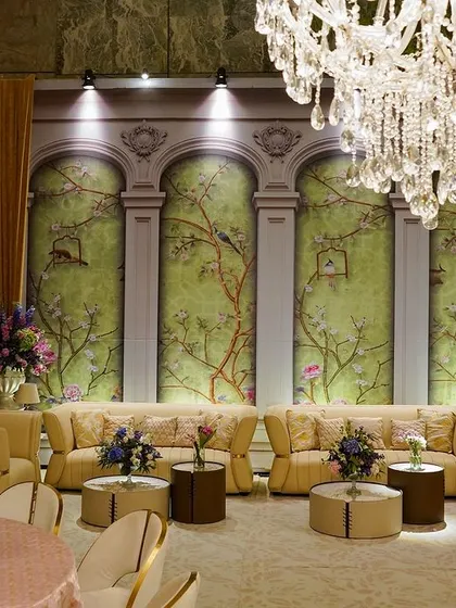 A wide view of the elegant lounge area, with its comfortable sofas, chinoiserie mural, and sparkling chandeliers.