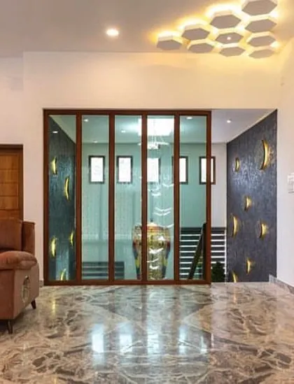 This living room uses a glass and wood folding partition to separate the staircase area, creating a visually interesting feature. The Italian marble flooring and honeycomb-patterned ceiling light add to the luxurious feel.