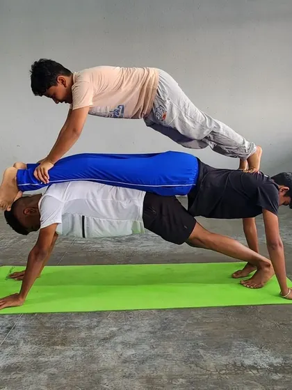 This impressive three-person plank requires precise alignment and communication between all participants.