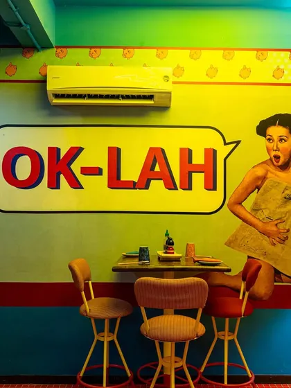 A close-up on the iconic "OK-LAH" wall art at The Fatty Bao. This shot isolates a memorable and Instagrammable moment in the restaurant, showcasing the playful and graphic-heavy interior design.