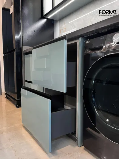 This image showcases our pull-out drawers next to an integrated washing machine. We design our kitchens to accommodate all your appliances seamlessly, maintaining a clean and uncluttered look.