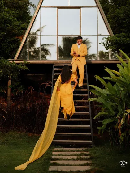 The bride, with a long flowing yellow train, walks up the stairs towards the groom, creating a beautiful, fairy-tale-like image.