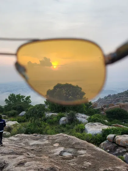 A creative shot of the sunset reflected in a pair of sunglasses, capturing the beauty of the golden hour on a trek.