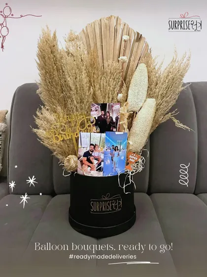 A personalized birthday bouquet in a sleek black box, filled with pampas grass and photos of the recipient.