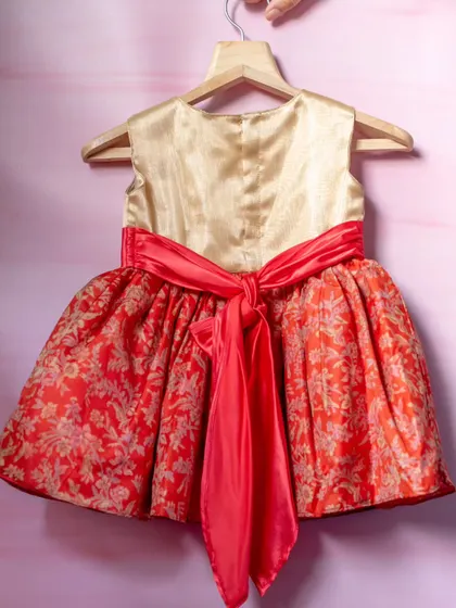 A vibrant dress in red and gold brocade. The rich fabric and festive colors make this a perfect choice for holiday celebrations or cultural events, finished with a bright coral sash.