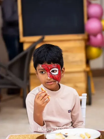 It's not a party without some fun transformations! Here, a young guest gets his face painted like Spider-Man, adding another layer of interactive fun to the event.