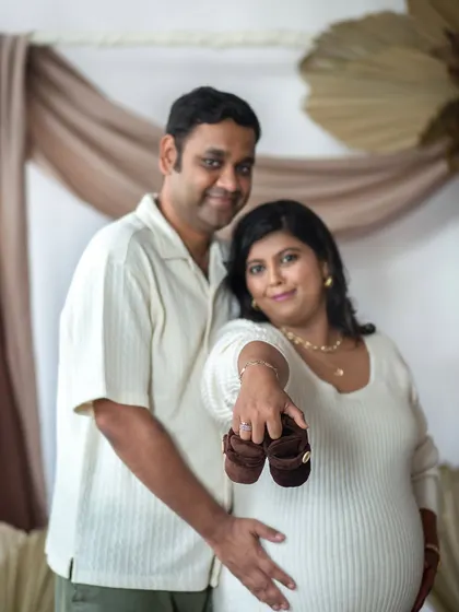 A creative shot focusing on the tiny baby shoes, with the happy couple in the background. This is a wonderful detail shot for a pregnancy announcement.