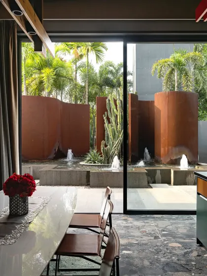 A view from inside the KEUS office, looking out onto the sculptural Corten steel and water installation. The large glass window frames the landscape, making it a powerful visual element for the workspace.
