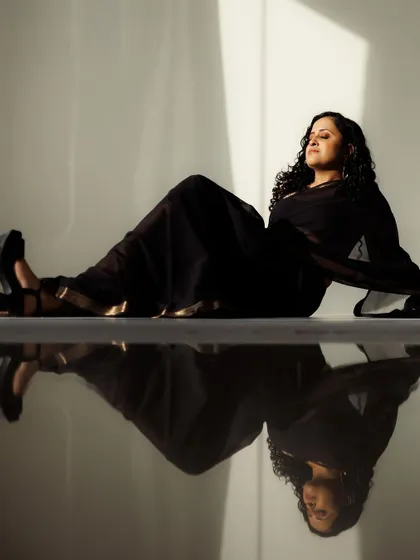I love playing with light and shadow in photoshoots. This artistic shot captures a modern, elegant look with a sheer black saree. The makeup is subtle and glowing, and the reflection on the floor adds a beautiful, dramatic effect to the overall composition.