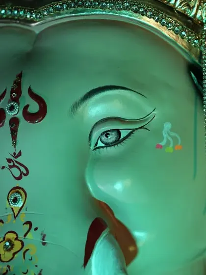 A close-up on the expressive eyes and detailed facial paintings of the Palmbeach Cha Vighnaharta idol.