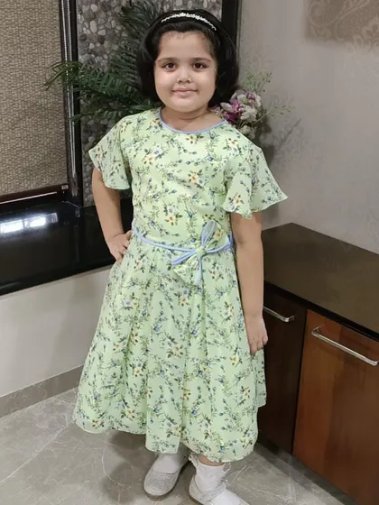 A happy customer posing in her light green floral dress. The flutter sleeves and simple tie-belt make this a comfortable and pretty choice for everyday wear.