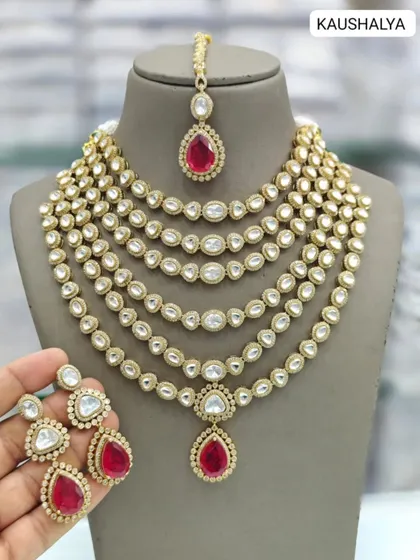 A closer look at our multi-layered Kundan necklace set. This piece comes with a matching maang tikka and earrings, and is available in both ruby red and emerald green, providing a complete and grand bridal solution.