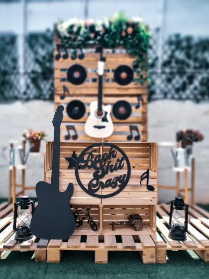 For the bride who wants to rock, this "Bach Shit Crazy" theme is a guaranteed hit. The setup features a rustic wooden backdrop, guitars, and vinyl records for an authentic rock and roll party vibe.
