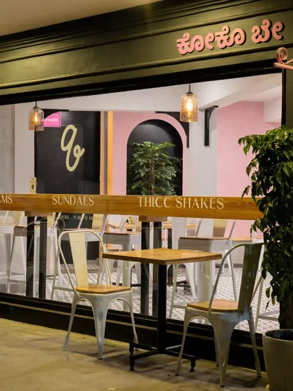 The outdoor seating area at Qoqobae, designed for customers to enjoy Bengaluru's pleasant weather. This space extends the cafe's footprint and enhances its street presence, making it a visible and active part of the neighborhood.
