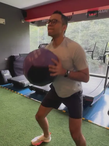 A client holds a medicine ball during a squat, adding an external load to this fundamental movement pattern.