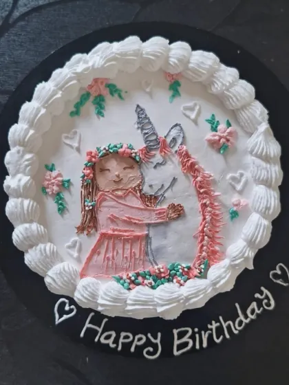 A lovely hand-piped cake showing a girl hugging a unicorn. This buttercream art style is a great way to create a unique and personal design.
