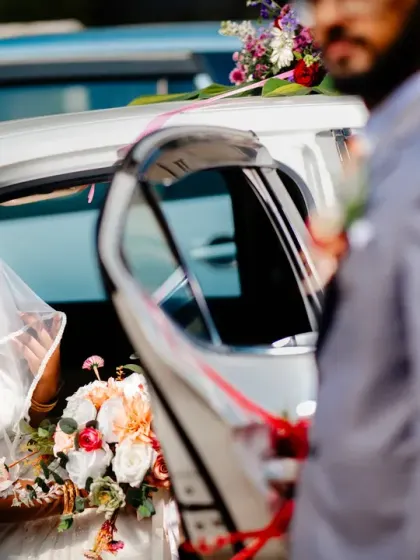 The groom waits as his bride arrives, her smiling face visible through the car window.