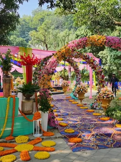 A beautiful floral archway entrance for a Mehendi ceremony, leading to a colorful and festive celebration space.