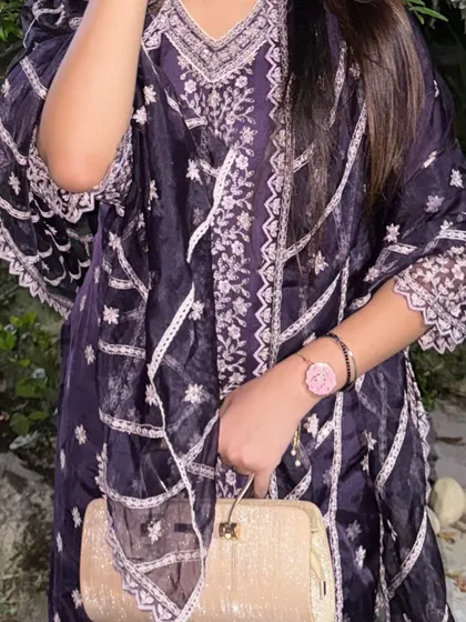 A close-up of the outfit, focusing on the intricate embroidery and the elegant clutch.