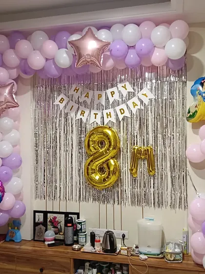 A princess-themed 8th birthday decoration. This setup includes a balloon arch in pink, purple, and white, a silver tinsel curtain, and foil balloons of Snow White and stars.