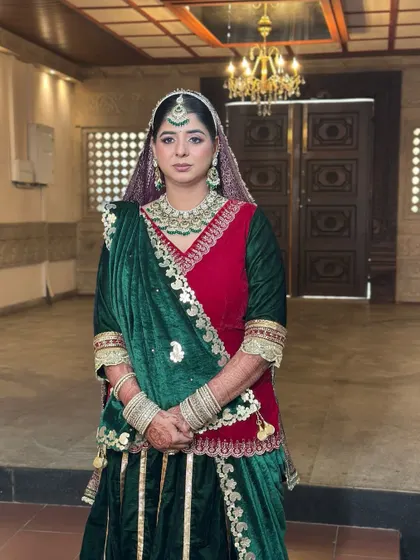 A full-length portrait of the sister of the groom in a stunning Rajasthani poshak. The makeup is regal and elegant, with defined eyes and a flawless base.