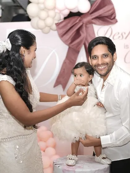 A beautiful family photo capturing the cake-cutting moment at Deshnaa's bow-themed first birthday party.