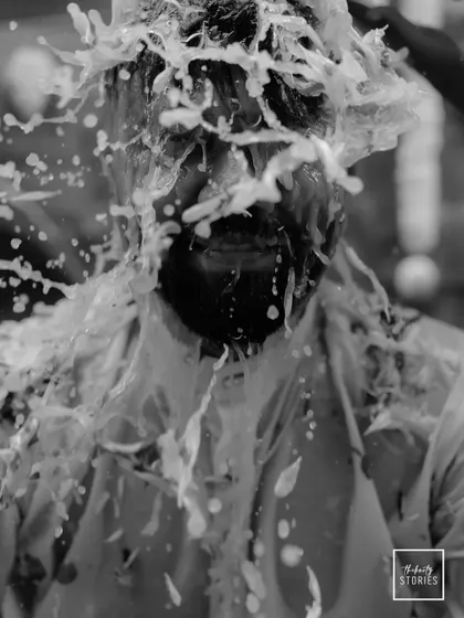 A dramatic black and white action shot of the groom being splashed with water during his Haldi. The monochrome edit freezes the motion and adds a powerful, artistic feel.