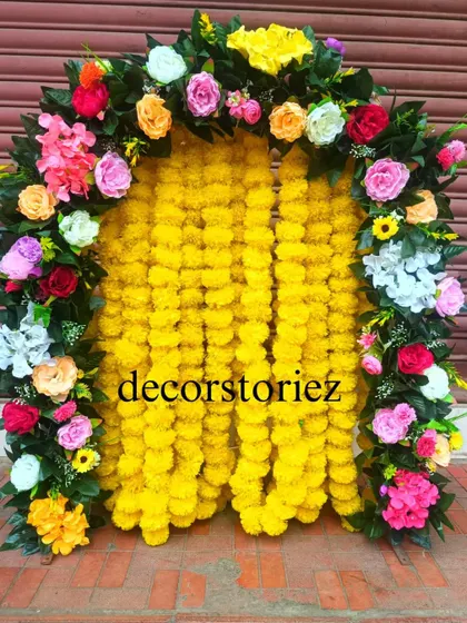 A vibrant and traditional ready-to-install makhar, perfect for Haldi ceremonies or Ganpati festival decor. This backdrop features dense yellow marigold garlands framed by a colorful arch of artificial roses, creating a classic festive look.
