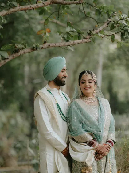 A romantic shot of the couple under the trees. Her makeup is soft and natural, perfectly fitting the outdoor setting.