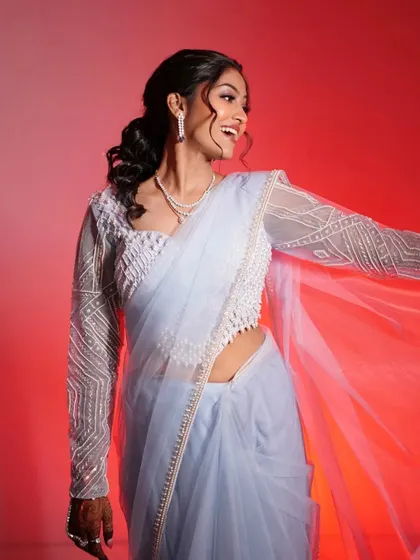 A fun, happy shot of the bride against a vibrant red background. Her smile is infectious, and her makeup looks flawless and radiant.