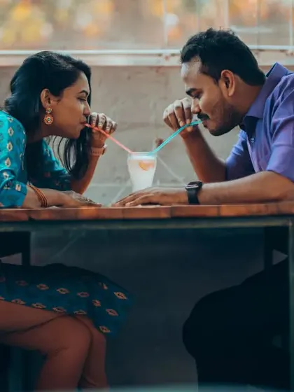 A classic romantic pre-wedding shot of a couple sharing a drink. The close framing and shared glance create an intimate and sweet memory.