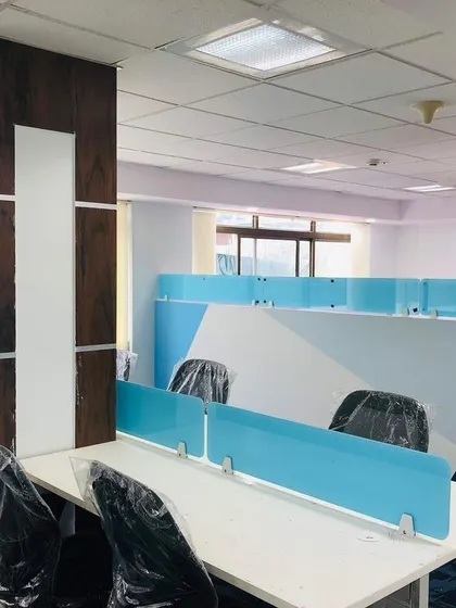 A photo of the completed office workstations. The blue translucent dividers and wood-clad structural columns from the render have been implemented to create a cohesive and functional office.