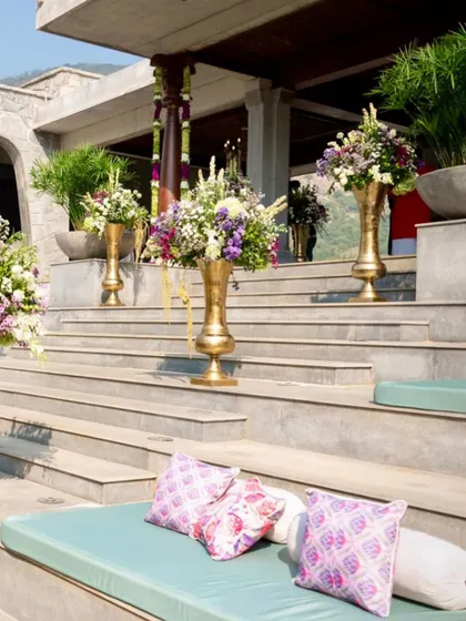 The steps of the venue are decorated with large brass vases filled with flowers.