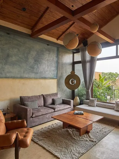 In the heart of Bangalore, we designed the Magnolia penthouse to be an urban oasis. This living space, with its natural timber roof and pigmented cement walls, opens up to a lush terrace, blurring the line between indoor comfort and outdoor serenity.