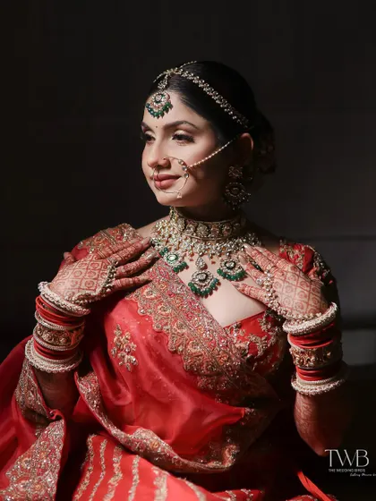 A portrait that highlights the bride's stunning jewelry. With her hands delicately placed on her chest, the focus is on the intricate details of her necklace, mehndi, and traditional attire.