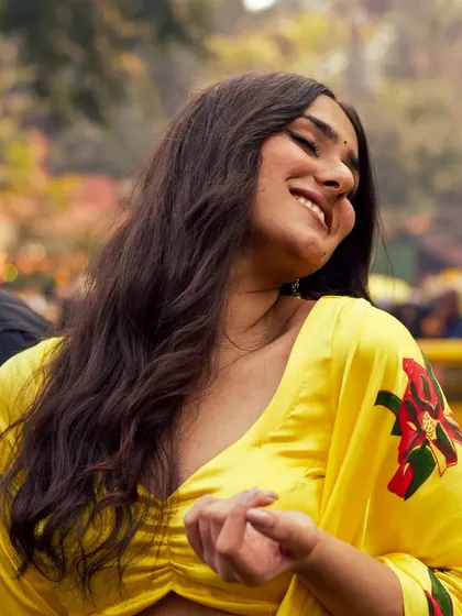 A candid, joyful portrait of a beautiful person smiling at a pride event. The warm light and genuine expression celebrate love and self-acceptance.