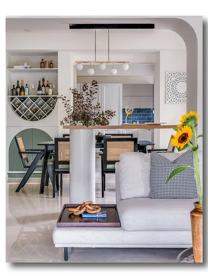 A view through an archway into a dining and bar area, with a sunflower adding a pop of color in the foreground. This shot highlights the home's layered design and the seamless flow between different functional zones.