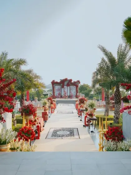 The long aisle, decorated with bursts of red florals and a mosaic-patterned runner, creates a grand processional path. This view showcases how we design the entire guest journey, building anticipation for the ceremony.