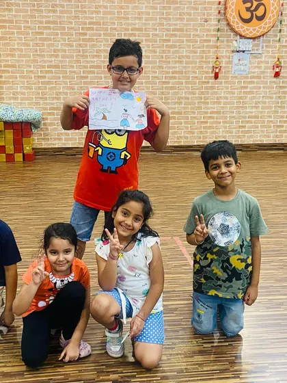 A group of happy kids showing off their drawings after an art class. The boy in the center is proudly displaying his colorful creation. Making art together is a great way to bond.
