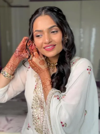 A candid moment of her adjusting her earring. The makeup is fresh and light, perfect for enjoying the wedding festivities.