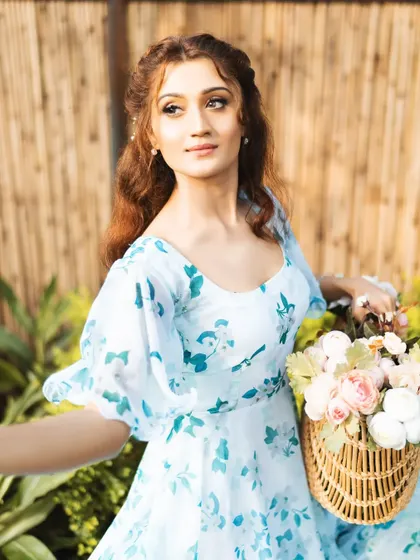 A bright, airy outdoor portrait for a fashion brand. The model is holding a basket of flowers, which adds a lovely, romantic touch to this lifestyle shot.