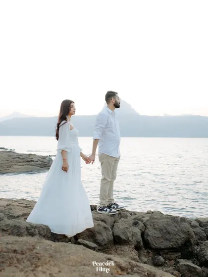 A classic romantic pose against the vastness of the lake and mountains. This pre-wedding shot captures the couple holding hands, looking towards the horizon and their future.