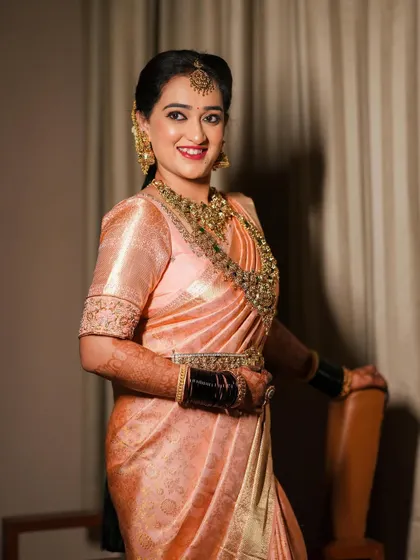A bride in a lovely peach Kanjivaram saree, her blouse featuring simple but elegant embroidery.