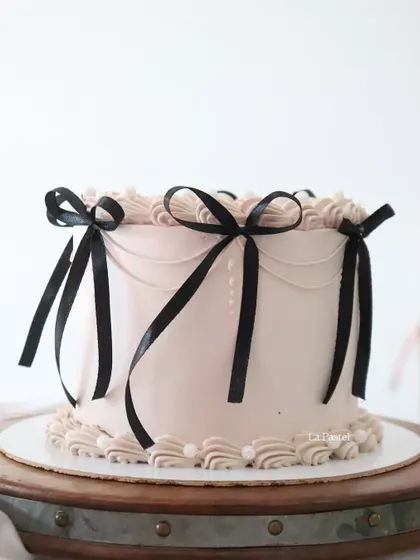 A full view of the chic cake with black ribbon bows, perfect for a sophisticated party.