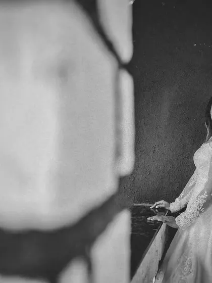 A black and white bridal portrait with a creative foreground blur. This technique draws the viewer's eye directly to the bride's happy expression.