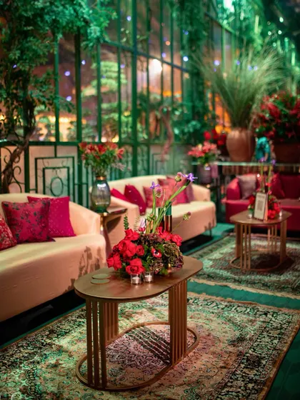A comfortable and stylish lounge area with Persian rugs and floral arrangements, perfect for conversations away from the main stage.
