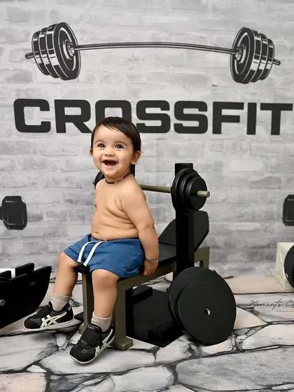 A huge smile from our little gym enthusiast. His pure joy is evident as he sits on the bench, surrounded by his tiny workout equipment.